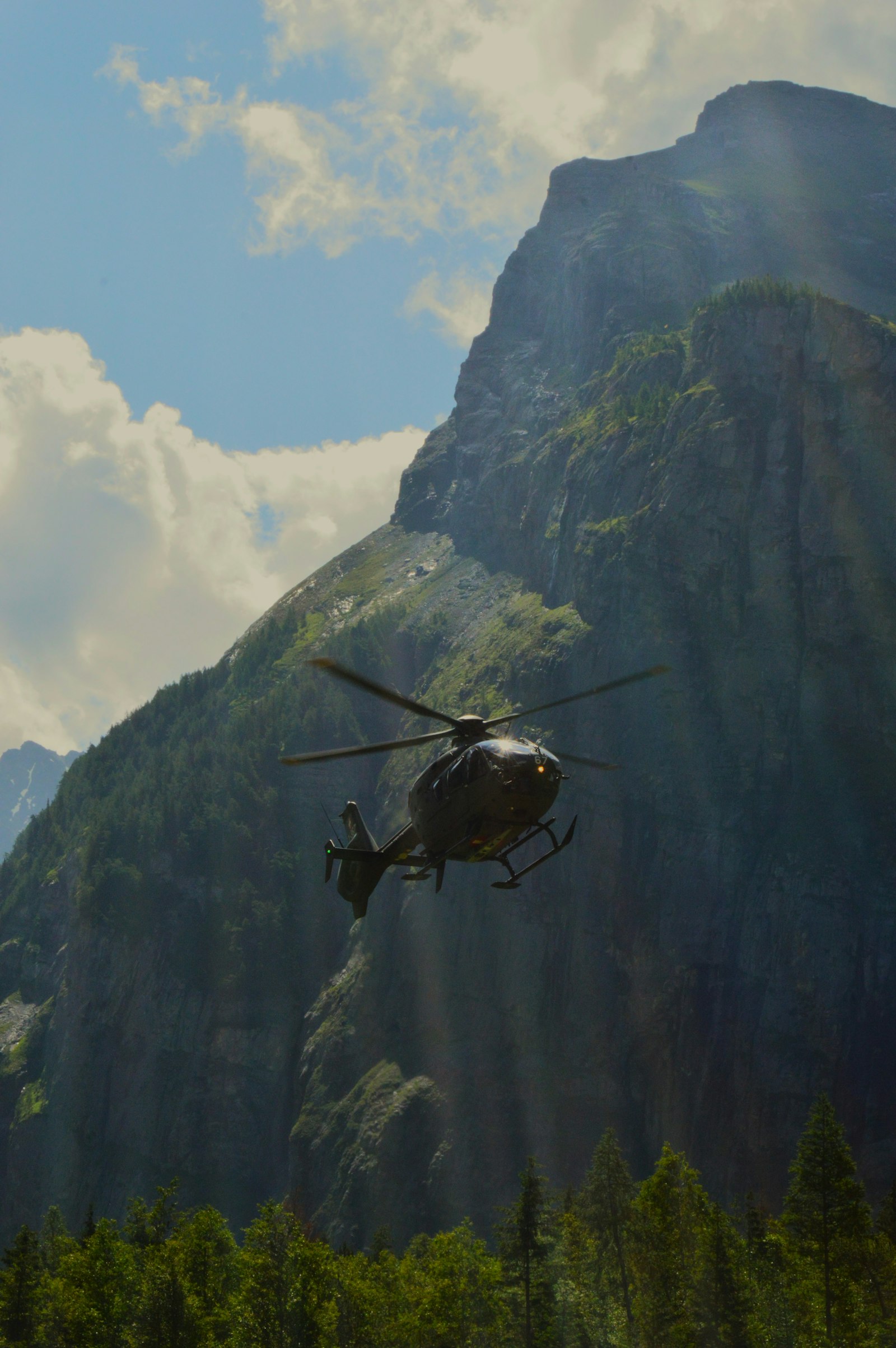 Rescue helicopter flying over rugged mountain terrain